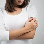 a woman scratches her arm from itchy bed bug bites